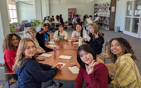 Ten students sit around a table and talk during Conversation Club.
