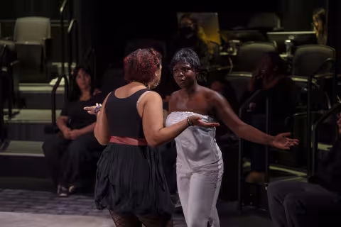 Two students performing "The Drunke City" at UAlbany in a darkened theatre