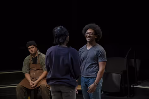 two actors, one of them seated, perform "The Drunken City" during a rehearsal at UAlbany inside a theatre