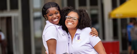 Two women in polo shirts smiling at the camera.