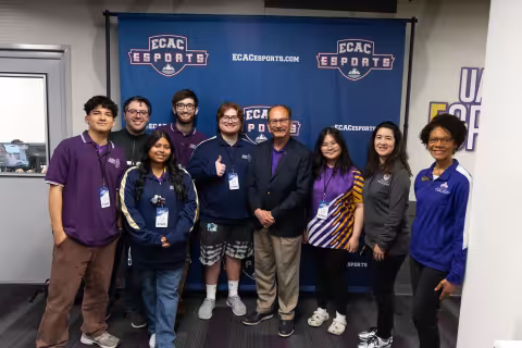 President Rodriguez meets with the UAlbany Esports team in front of a ECAC Esports banner.