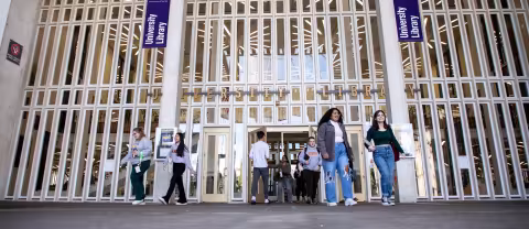 Students walk in and out of the University Library's main entrance.