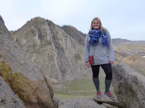 A Coverdell Fellow stands outside with the Mongolian mountains in the background.