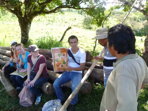 Jeancarlo sits on a bench in Costa Rica, holding a public health sign. 
