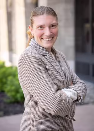 Chiara Calicchia in a light brown jacket, smiles, arms folded