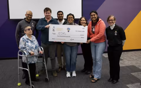 Group photo of smiling people holding a check