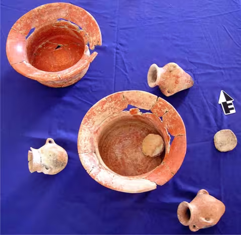 A cache of five ceramic vessels and three ceramic disks.