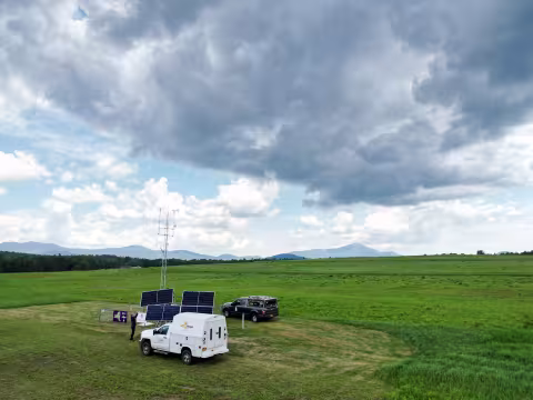 A drone image offers an ariel view of the Mesonet site in Lake Placid with the Adirondack Mountains behind it.