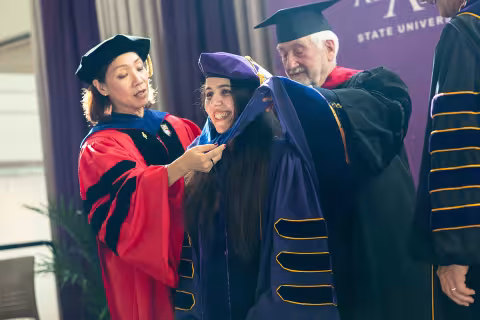 Najm on stage at the doctoral hooding with the Provost and her mentor.