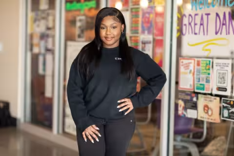 Nakisha Williams, dressed in black, stands in front of a window filled with posters