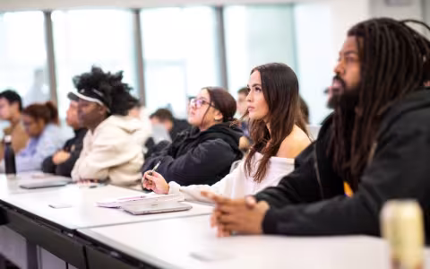 A group of students seated in a classroom taking notes