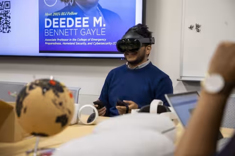 A man in a VR headset uses a remote control at a table