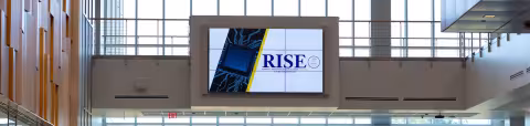 A large screen displays the Research & Innovators Startup Exchange (RISE) logo inside the ETEC building at UAlbany.