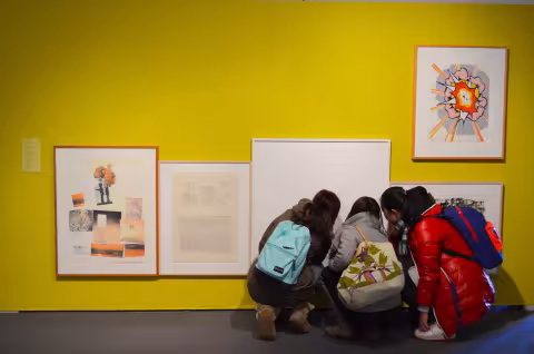 Students bending down looking closely at art in art museum.