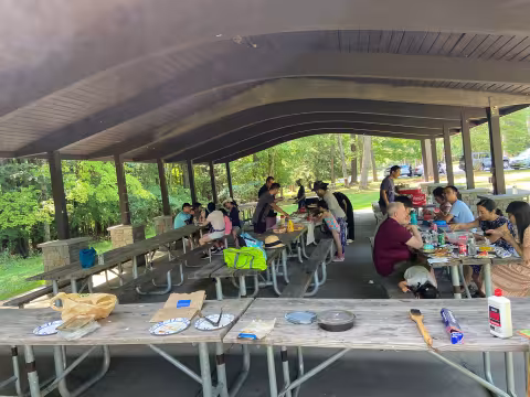 The UAlbany Asian Coalition of Professionals guests gathered at picnic table under pavilion