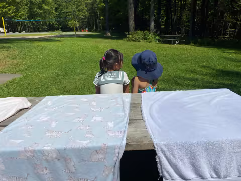 Two children are sitting together on a bench outside