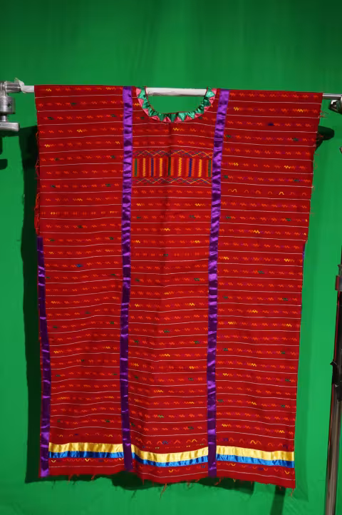 A woman's red fabric huipil with purple, yellow and blue silk ribbons.