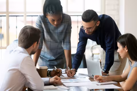 A group of young professionals working on a project at a conference table.
