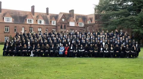 A large group of students at the University of Cambridge pose for a picture in the campus quad.