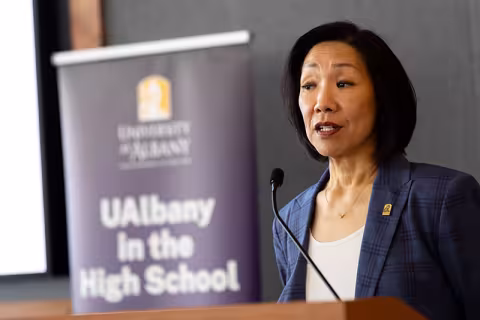 UAlbany Provost and Senior Vice President Carol Kim speaks at a podium with a sign behind her that says "UAlbany in the High School"
