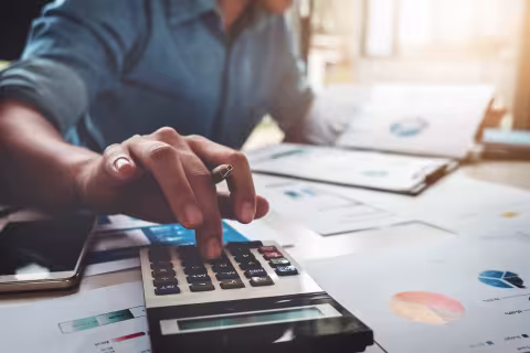 A man using a calculator while reviewing pie charts and graphs