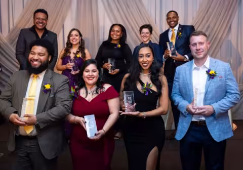 a group of smiling. dressed-up people hold awards