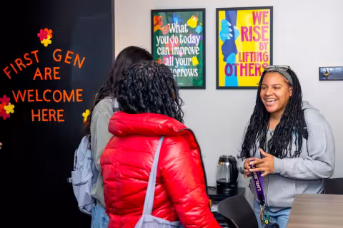 Three people having a conversation in an office with inspirational posters.