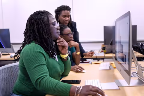 A professor working with two students at computers.