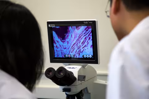 Two researchers looking at a monitor inside the UAlbany College of Engineering and Applied Sciences lab.