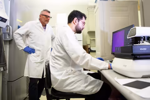 Two researchers in a UAlbany nanotechnology lab looking at data on a computer.