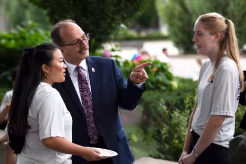 President Rodriguez speaking with two students on the Podium.