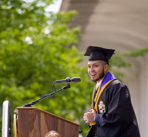 A graduating student speaks at a podium during commencement.