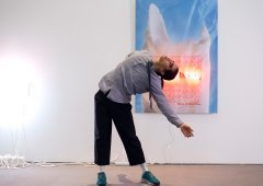 A person leans back in front of an art piece hanging on a wall.