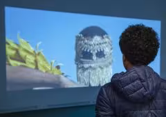A person stands in front of a projection, watching it.