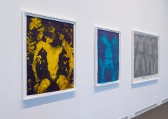 A white wall with three art pieces hanging on it.