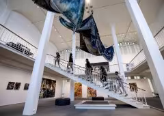 Museum visitors ascend a staircase, viewing an installation.