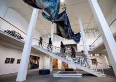 Museum visitors ascend a staircase, viewing an installation.