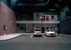 Two cars parked outside of a building at night.