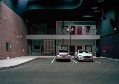 Two cars parked outside of a building at night.