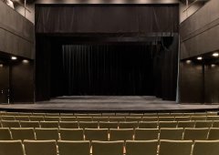 partial shot of small proscenium stage with drab green seats
