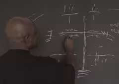 A person draws lines on a chalkboard.
