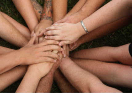 A group of people put their hands together in a pile.
