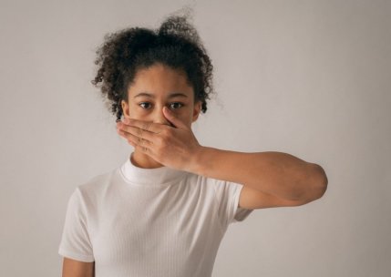 preteen of color with hand covering her mouth