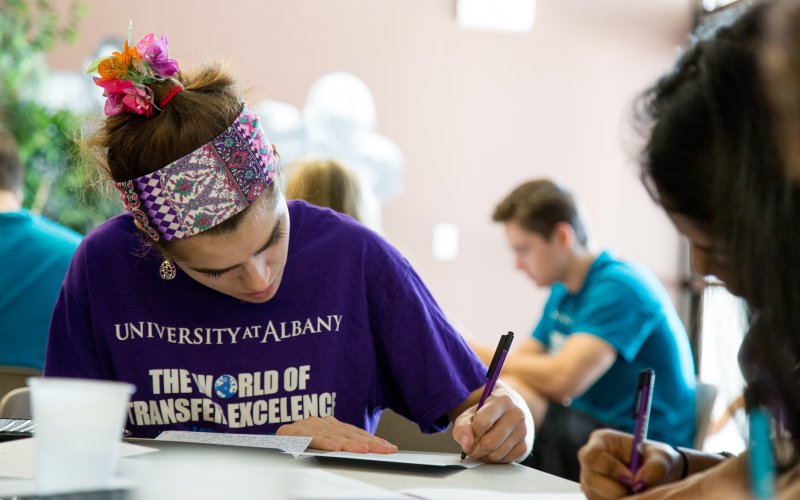 A student writes in a notebook during a living-learning community service day