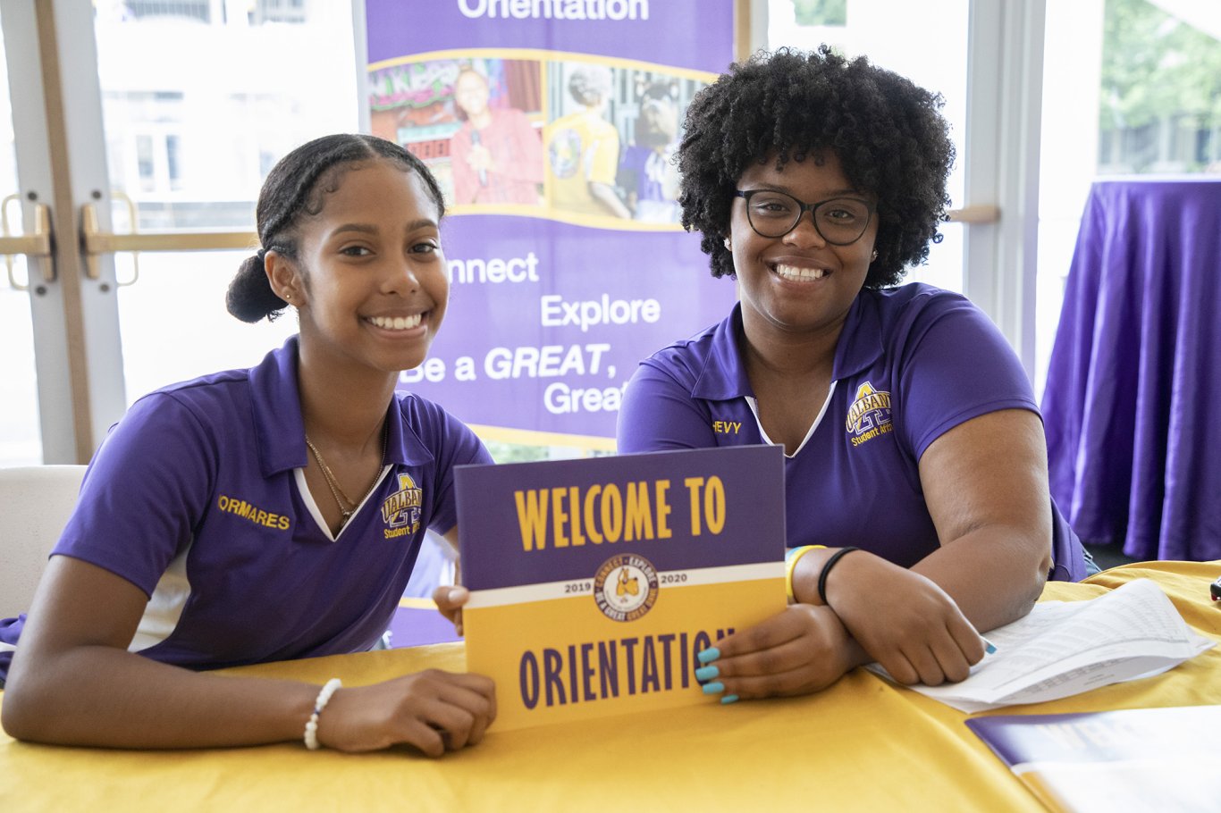Two orientation leaders holding a 'Welcome to Orientation' sign.