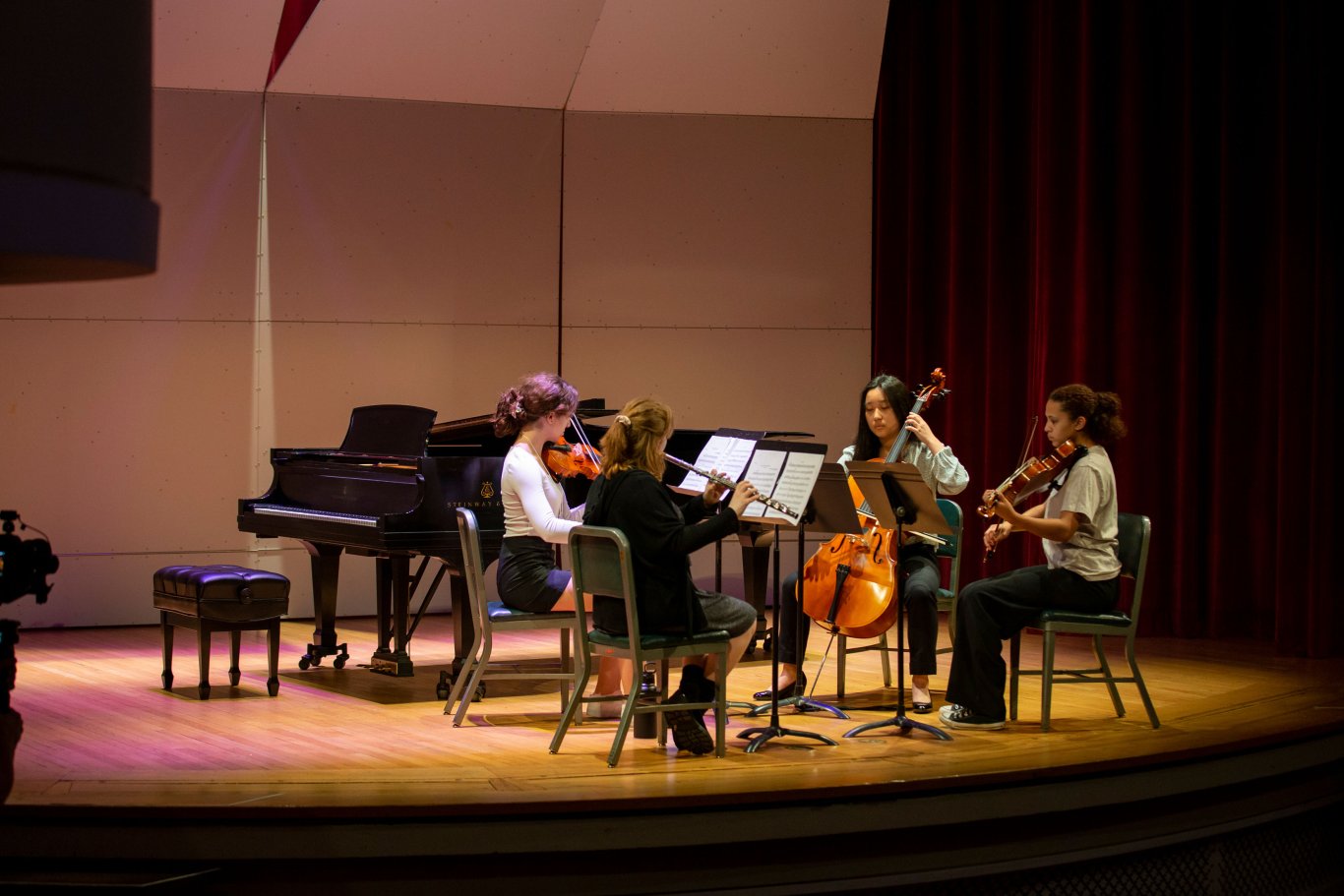 Four seated students perform on stage with three string instruments and one woodwind at UAlbany Showcase.