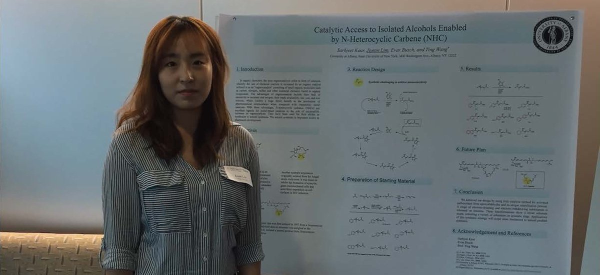 Team member Jiyeon stands before a poster describing her research at the undergraduate research symposium at the University at Albany