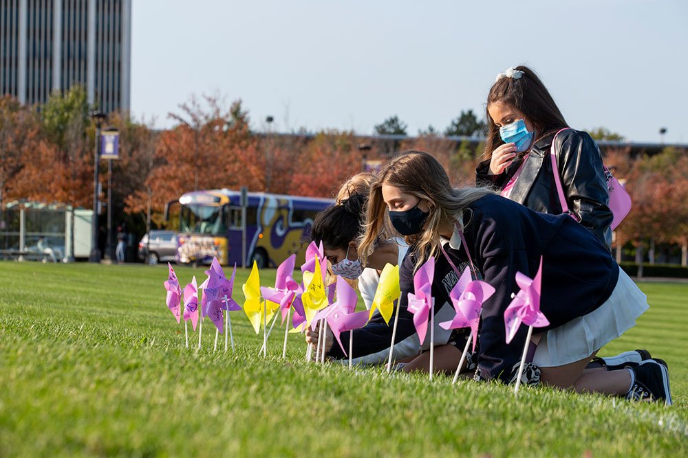 Students outside putting pinwheels in the grass.