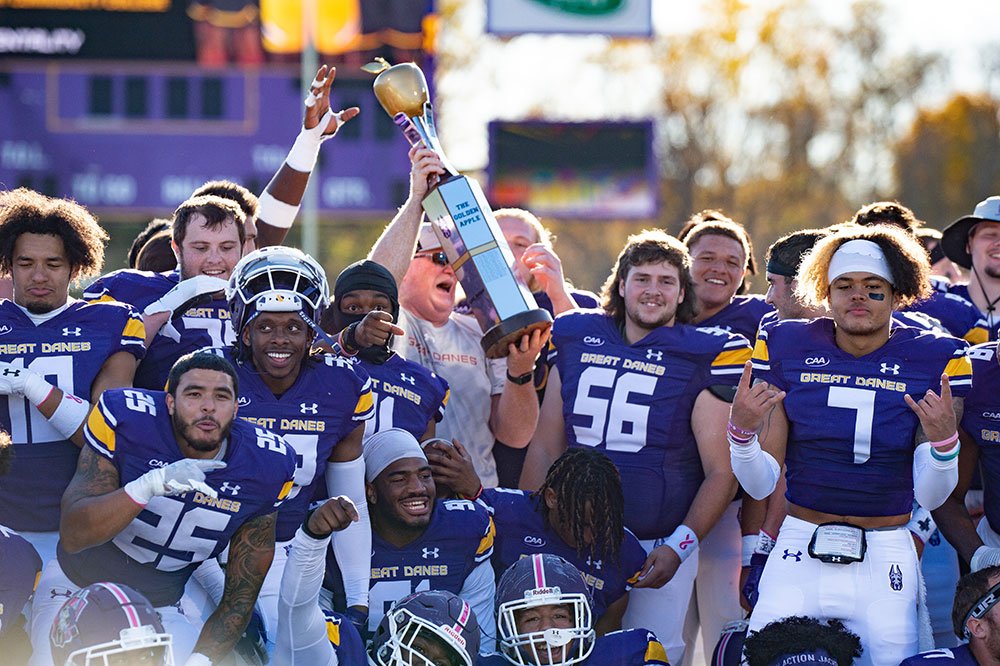 UAlbany football players holding a trophy.