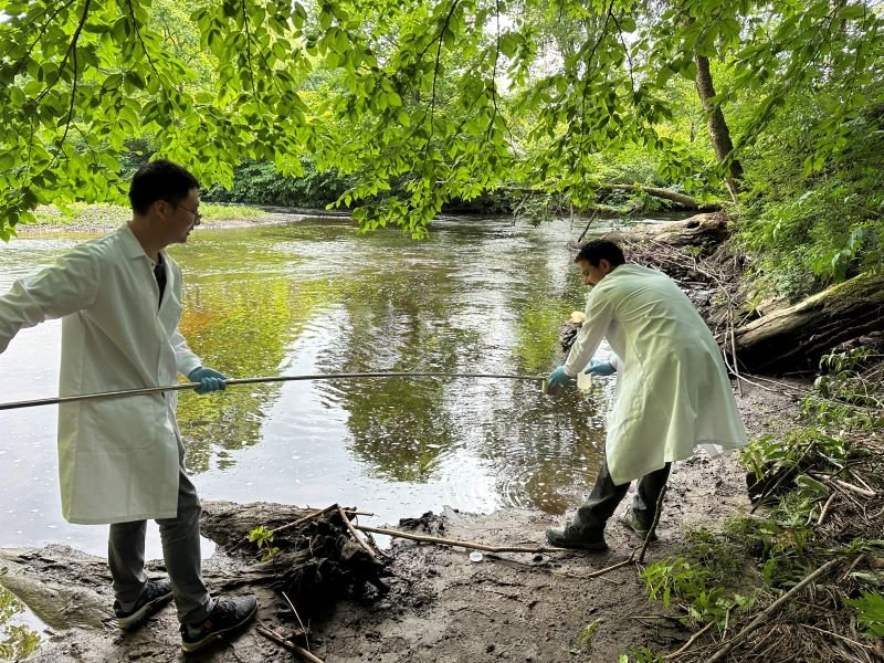 Group photo of lab members collecting samples in in a pond.
